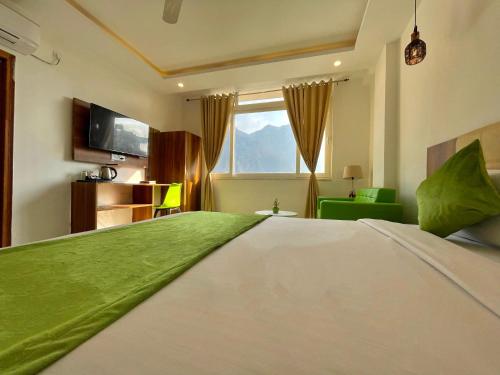 a bedroom with a large bed with a green blanket on it at Wanna Stay Rishikesh in Rishīkesh