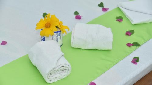 a table with towels and a flower in a vase at Prem Nadee Hotel in Dambulla