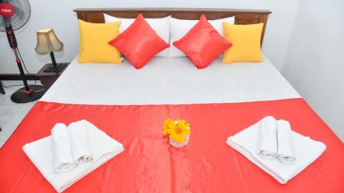 a bed with white towels and yellow and red pillows at Prem Nadee Homestay in Dambulla