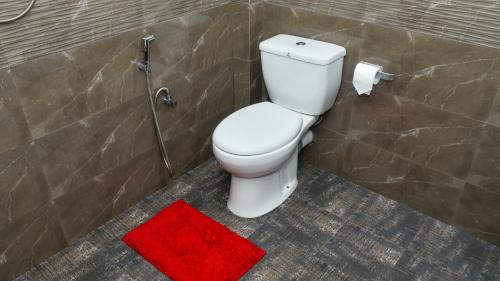 a bathroom with a toilet and a red rug at Prem Nadee Homestay in Dambulla