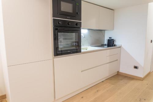 una cucina con mobili bianchi e un forno a microonde di !Subway to Duomo! Modern loft with AC and free wifi a Milano