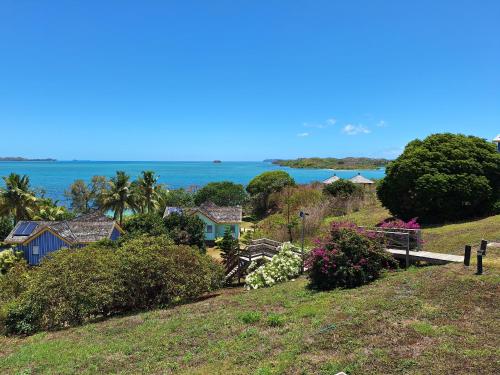 a house on a hill with the ocean in the background at Beach House Lodge in Poum