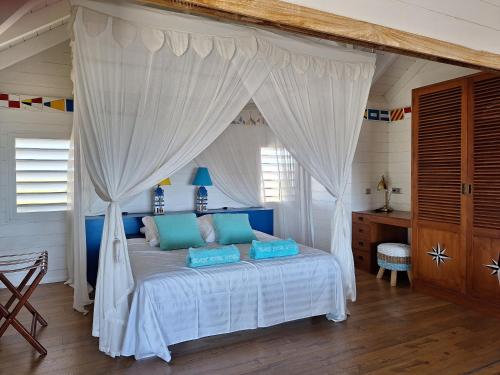 ein Schlafzimmer mit einem weißen Himmelbett und blauen Kissen in der Unterkunft Beach House Lodge 