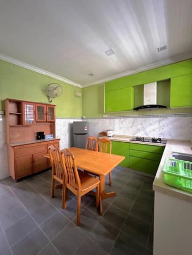 una cocina con armarios verdes y una mesa y sillas de madera. en Melody D’Rimba Sandakan, en Sandakan