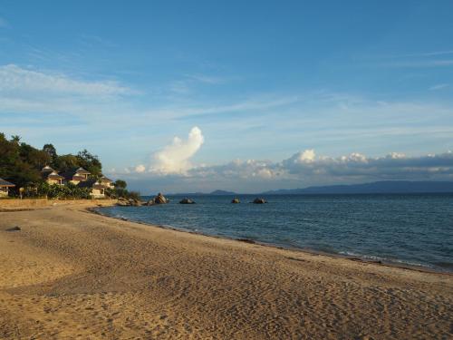 a sandy beach with rocks in the water at The Scenery Beach Resort in Baan Khai
