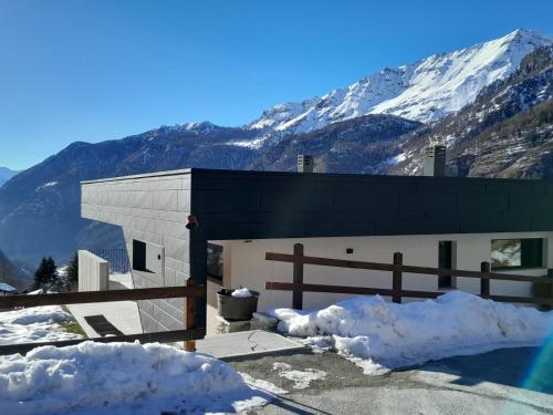 a snow covered building with mountains in the background at Casa Lo Tzé Relais - Indipendent house with amazing view in Valtournenche