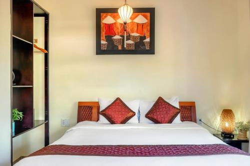 a bedroom with a large white bed with red pillows at Loc Phat Hoi An Homestay in Hoi An