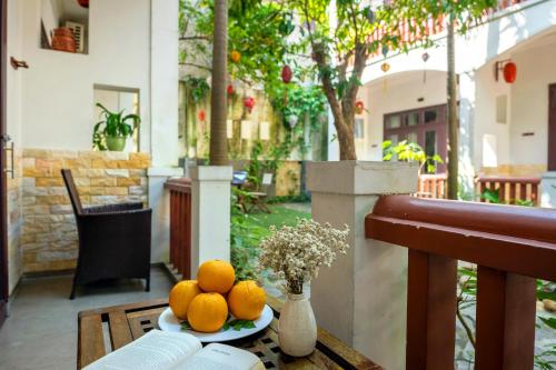 a plate of oranges on a table on a balcony at Loc Phat Hoi An Homestay in Hoi An