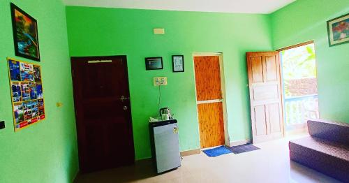 Habitación con paredes verdes, puerta y nevera. en CASA SOMANJO INN, en Calangute