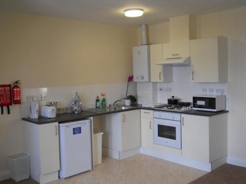 a small kitchen with white cabinets and appliances at Citystay Guest House in London