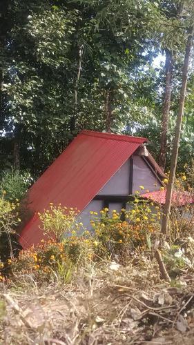 une petite maison avec un toit rouge dans les bois dans l'établissement Doko Resort, Kanyam, à Suryodaya