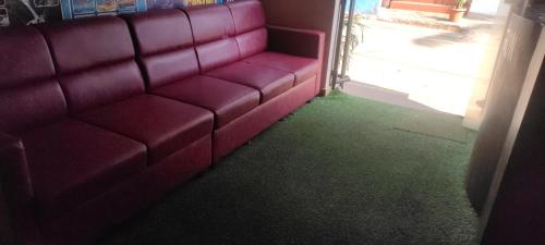 a red couch in a room with a green carpet at Hotel Shonarbangla in Calangute