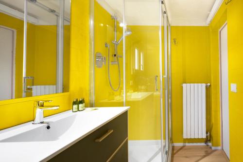 La salle de bains jaune est pourvue d'un lavabo et d'une douche. dans l'établissement Lussuoso Appartamento nel Cuore del Centro Storico, à Bologne