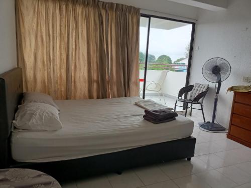 Schlafzimmer mit einem Bett und einem Fenster mit einem Stuhl in der Unterkunft Booking.com C View @ Sri Sayang Beach Resort in Batu Feringgi