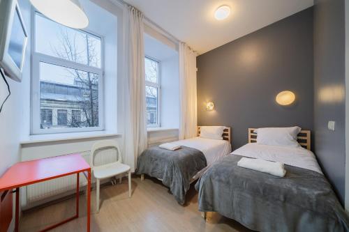 ヴィリニュスにあるHalės Guest House - Lollo Luxuryのベッド2台、テーブル、窓2つが備わる客室です。