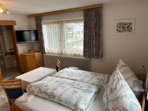 una camera da letto con letto, cuscini e finestra di Austrian Motel Heiss a Prutz