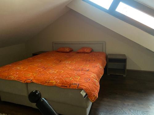 1 cama con edredón naranja en el ático en Apartman Pesic, en Vranje