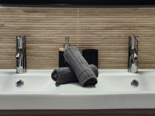een wastafel in de badkamer met 2 handdoeken en 2 kranen bij Appartement centre-ville proche lac, océan, vignes in Lesparre-Médoc