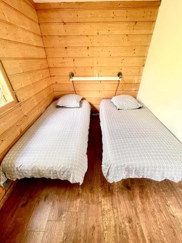 - 2 lits dans une petite chambre avec des murs en bois dans l'établissement Le petit chalet, à Chanas