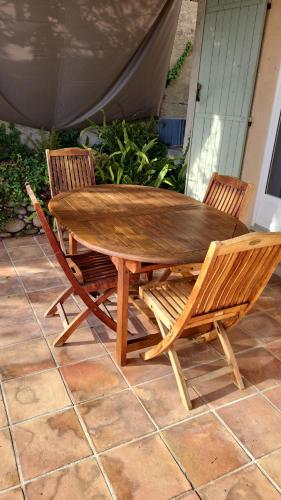 Une table et des chaises en bois sont disponibles sur la terrasse. dans l'établissement Villa les Gabians, à Saint-Laurent-du-Var