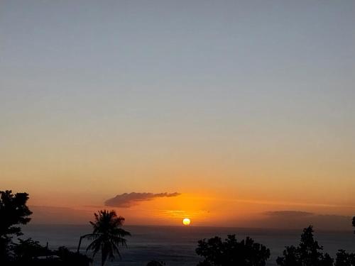 einen Sonnenuntergang mit der Sonne am Himmel in der Unterkunft Sous-les-tropiques in Vieux-Habitants