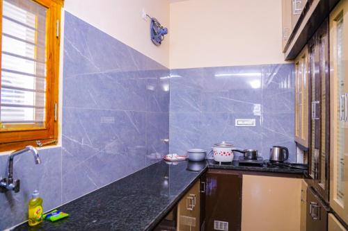 una cocina con encimeras negras y azulejos azules en SKV Residency, en Tirupati