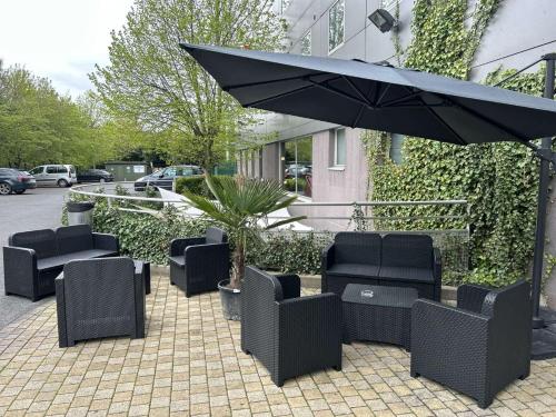une terrasse avec des chaises et un parasol dans l'établissement Standing Hotel Suites by Actisource, à Roissy-en-France