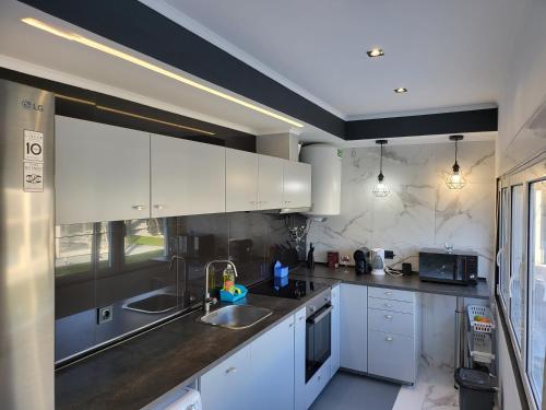 a kitchen with white cabinets and a sink at Aroeira Tropical Villa in Charneca