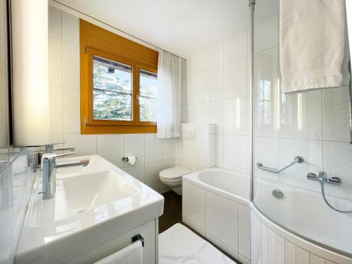 a bathroom with a sink and a tub and a toilet at Holiday flat for 6 people Sot Valos Lenzerheide centre in Lenzerheide