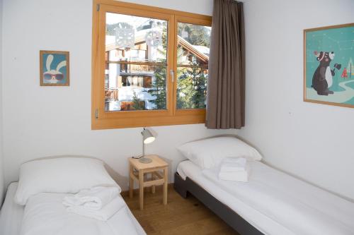 two beds in a room with a window at Holiday flat for 6 people Sot Valos Lenzerheide centre in Lenzerheide