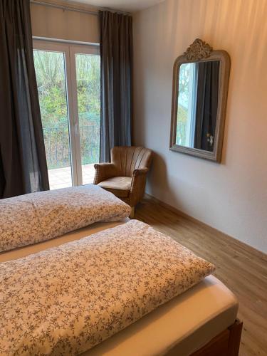 a room with two beds and a mirror and a chair at Ferienwohnung Rebblick in Müllheim