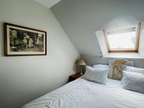 a bedroom with a bed with white sheets and a window at Le Clos des Anges, adorable Penty bord de mer in Séné