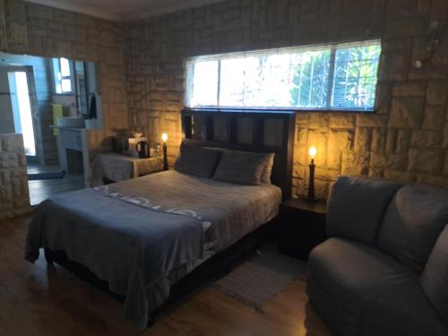 una camera con letto, divano e finestra di Meadows Guesthouse a Germiston