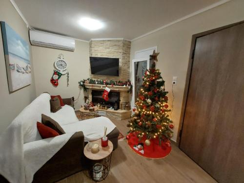 una sala de estar con un árbol de Navidad frente a una chimenea en Guesthouse Eirini Porto Germeno, en Aigósthena