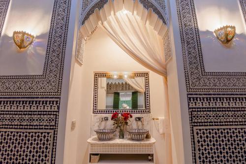 a hallway with two doors with a mirror and flowers at Riad Contessa & spa in Marrakesh