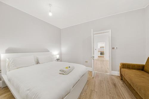 biała sypialnia z dużym białym łóżkiem i kanapą w obiekcie The Knightsbridge Deluxe Apart w Londynie