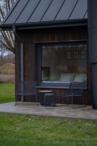 a building with a bed and two chairs on a deck at Daczowisko in Gruczno