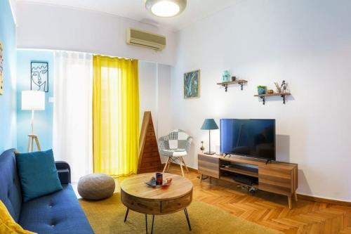 a living room with a blue couch and a tv at 4 Family and Friends - Acropolis view in Athens