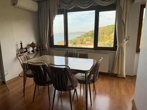 ein Esszimmer mit einem Tisch und Stühlen sowie einem großen Fenster in der Unterkunft 5+2 flat with bosphorus seaview in Istanbul