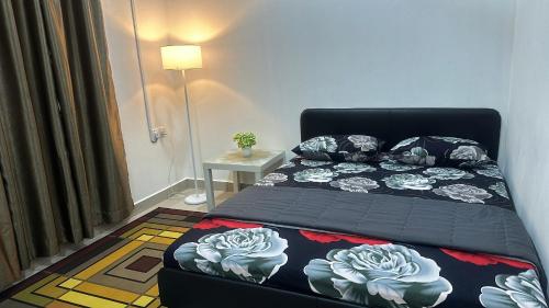 Un dormitorio con una cama y una mesa con una colcha con flores en Mummy Firdhan Homestay en Rembau