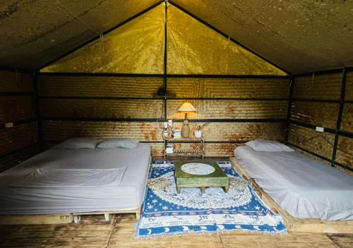 a room with two beds and a table in it at Con Dao Backpacker - LoCo Camping in Con Dao