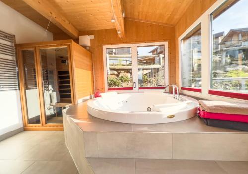 a large white tub in a bathroom with windows at 1A Chalet "Wolke" Wandern, Grillen, Wellness im Traumhaus in Wolfsberg