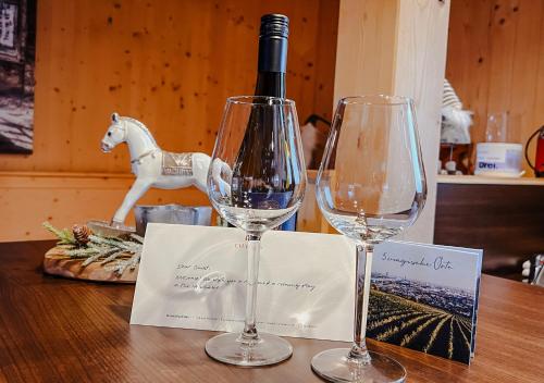 two wine glasses sitting on a table with a bottle of wine at 1A Chalet "Wolke" Wandern, Grillen, Wellness im Traumhaus in Wolfsberg