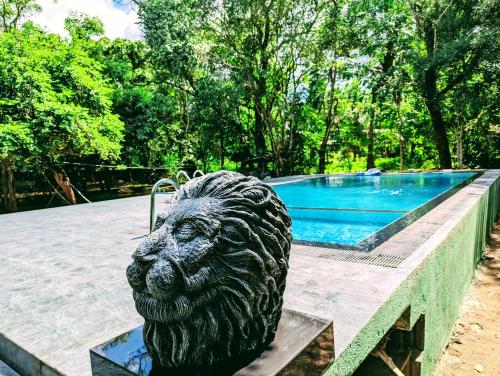 波隆納魯沃的住宿－Wildescape Polonnaruwa，狮子雕像坐在游泳池旁