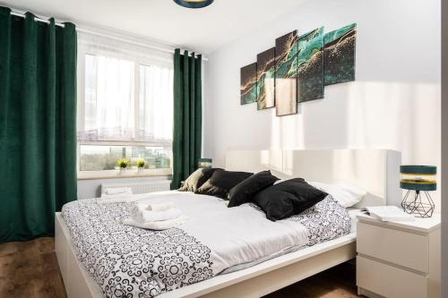 Schlafzimmer mit einem großen Bett und grünen Vorhängen in der Unterkunft Capital Apartments in Krakau