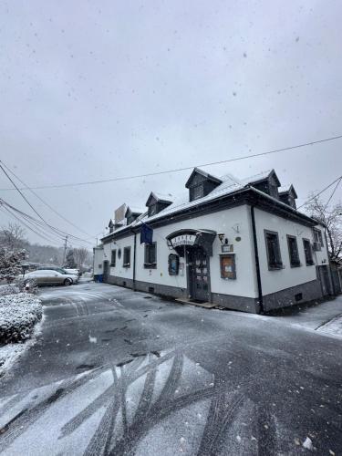 a white building on the side of a street in the snow at Jager Guesthouse in Sopron