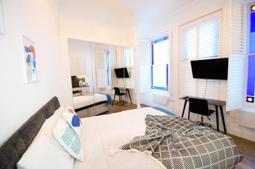 a bedroom with a bed and a desk and a television at Kensington Studios in London