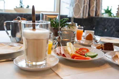 a table with a plate of food and a drink at Hotel Garni Helvetia in Ischgl