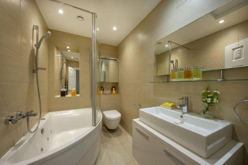 a bathroom with a sink and a tub and a toilet at Stunning Hyde Park Apartment in London