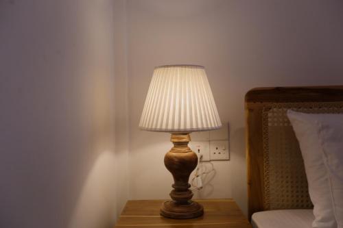 a lamp sitting on a table next to a bed at Coop Safari Hotel in Tissamaharama